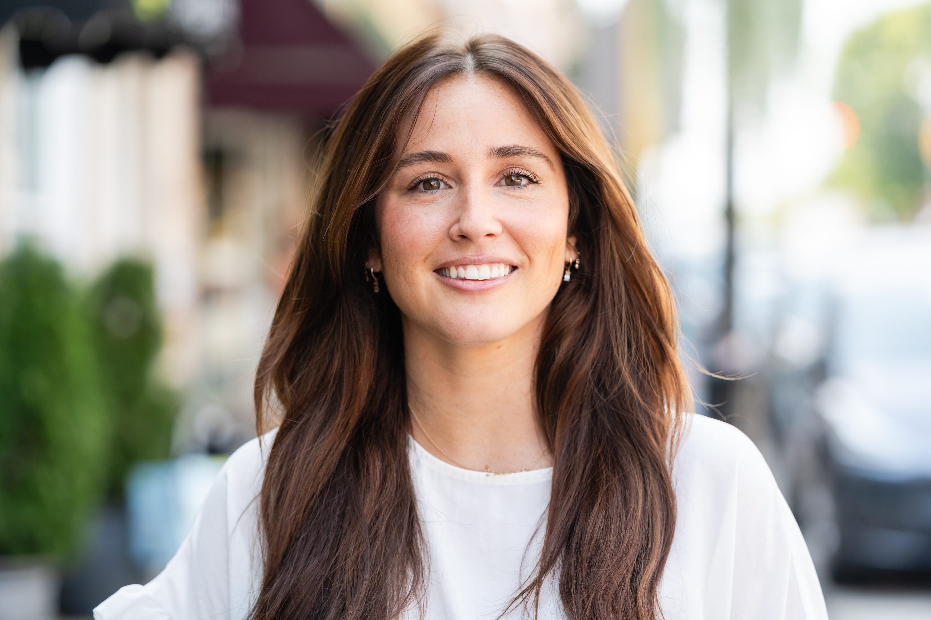 A woman with long brown hair wearing white shirt.