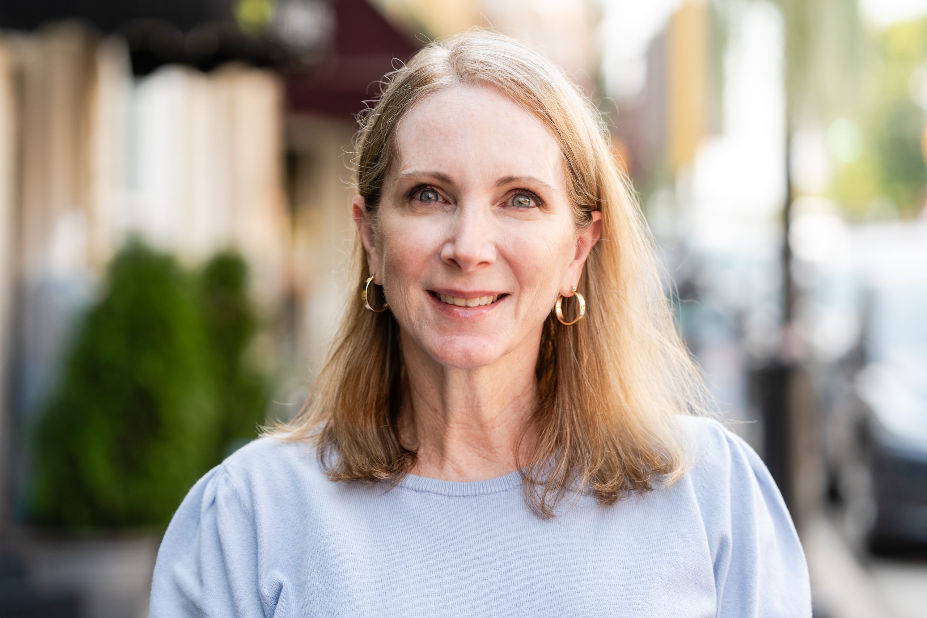 A woman with long blonde hair wearing a blue shirt.